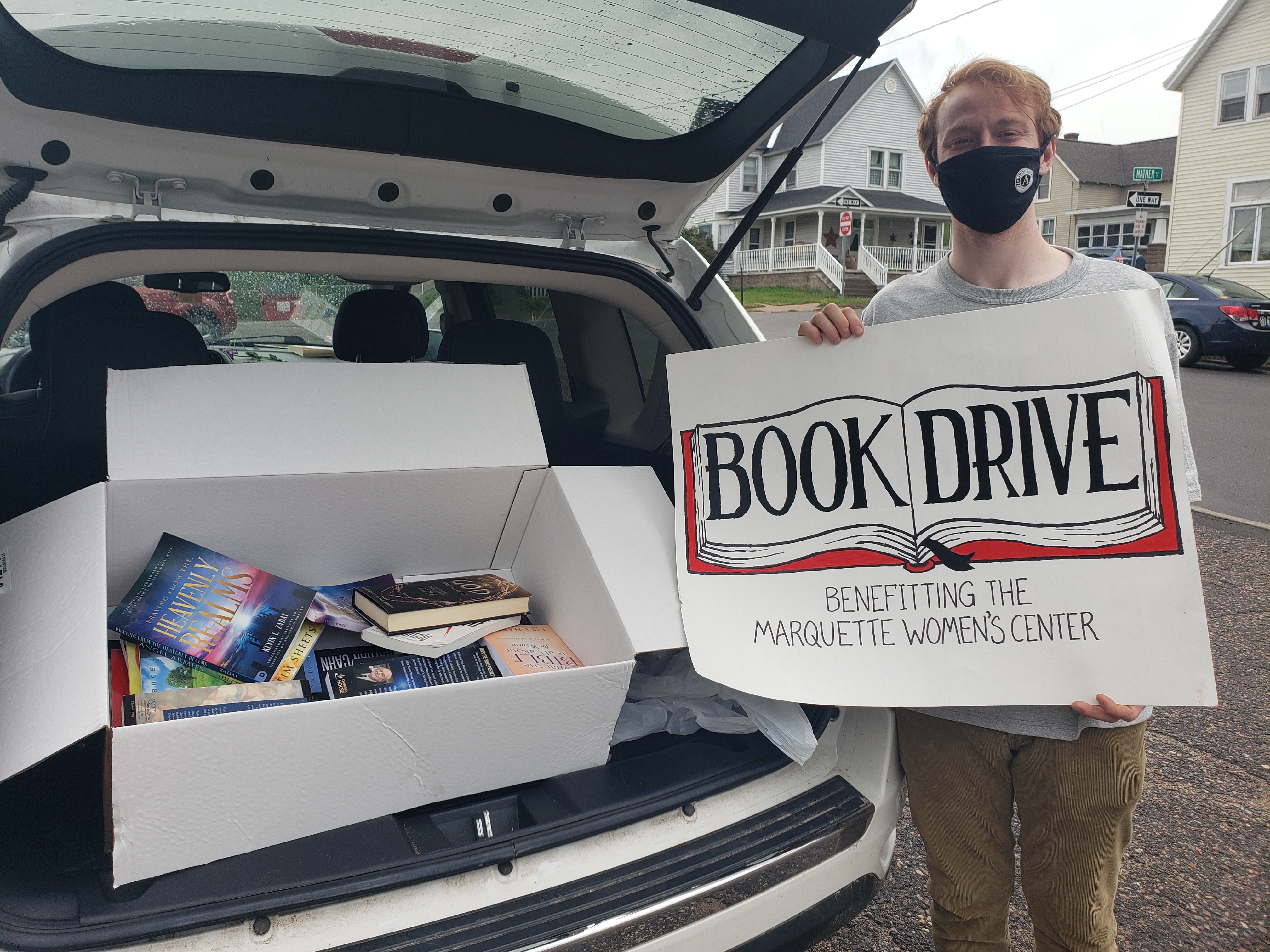 Man poses with a sign that says "Book Drive."